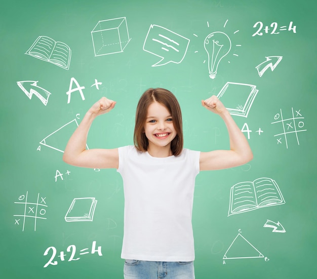 publicidad, gesto, escuela, educación y gente - niñita sonriente con camiseta blanca en blanco con brazos levantados sobre tablero verde con fondo de garabatos