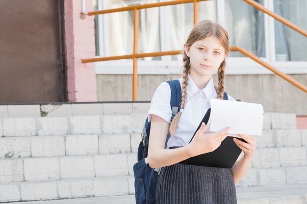 Publicidad de productos. Niño en edad escolar pequeño feliz presentando su producto. Niña con libros sonriendo y presentando productos o servicios. Nunca puedes equivocarte con este producto.