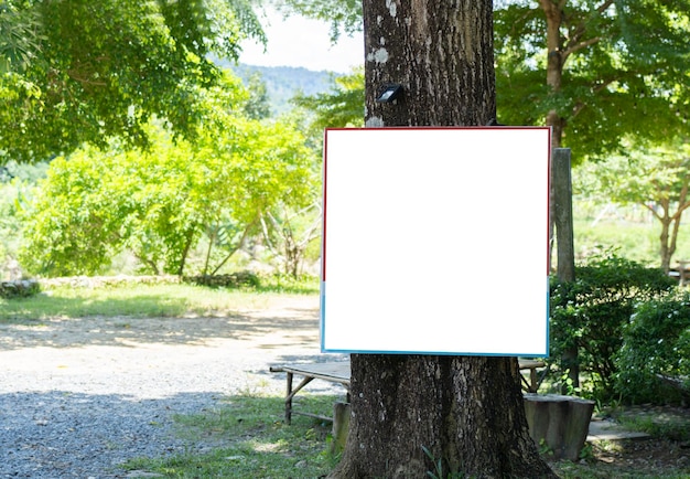 Foto publicidade ao ar livre branca em branco ou modelo de quadro colocado ao ar livre com fundo verde de árvore