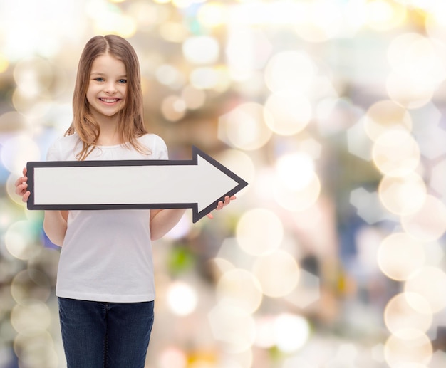 publicidade e conceito infantil - menina sorridente com seta em branco apontando para a direita