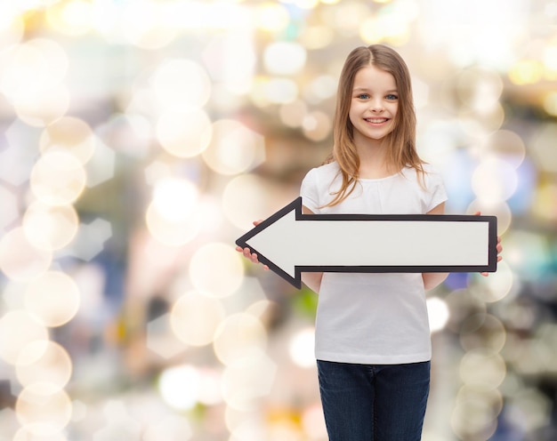 publicidade e conceito infantil - menina sorridente com seta em branco apontando para a esquerda