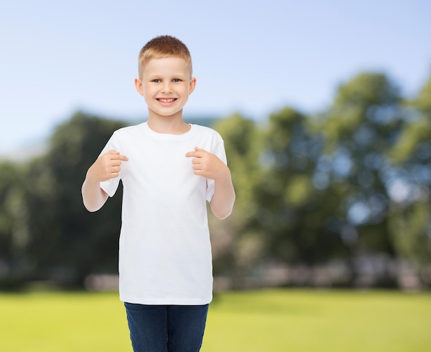 publicidade, verão, pessoas e conceito de infância - menino sorridente em camiseta branca em branco apontando os dedos para si mesmo sobre o fundo do parque