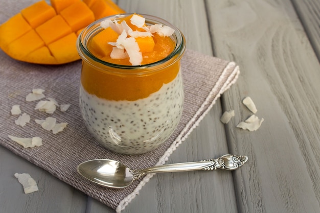 Pudding mit Chia-, Mango- und Kokosnusschips auf der grauen Serviette