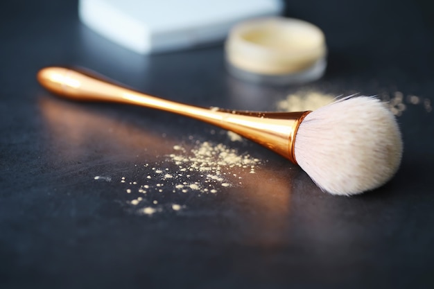 Foto puder- und make-up-pinsel. braunes pulver im hintergrund. make-up-produkte. stilkonzept.