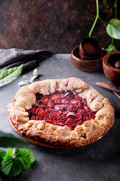 Puderzucker wird auf hausgemachten Kuchen mit Erdbeeren auf dem Tisch Sommergebäck mit gegossen