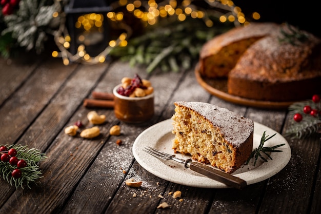 Pudim de bolo de natal tradicional com frutas e nozes com fundo escuro de decoração de natal