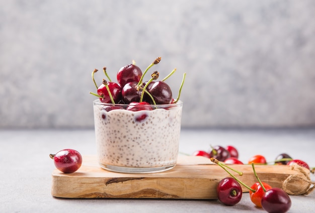 Pudim de Chia com cereja, iogurte natural, em copo sobre superfície cinza