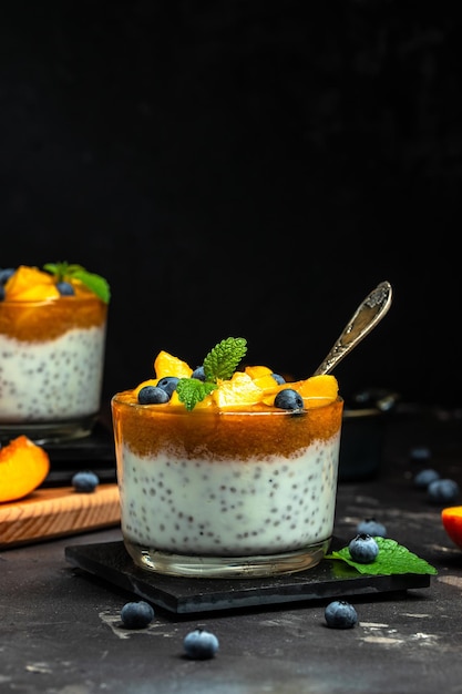 Pudim de chia saudável com iogurte e frutas Pêssego e mirtilo Sobremesa caseira com lugar de frutas para vista superior do texto