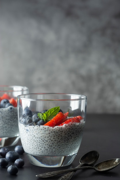 Pudim de chia saudável em um copo com frutas frescas. Café da manhã saudável. Comida escura foto comida.