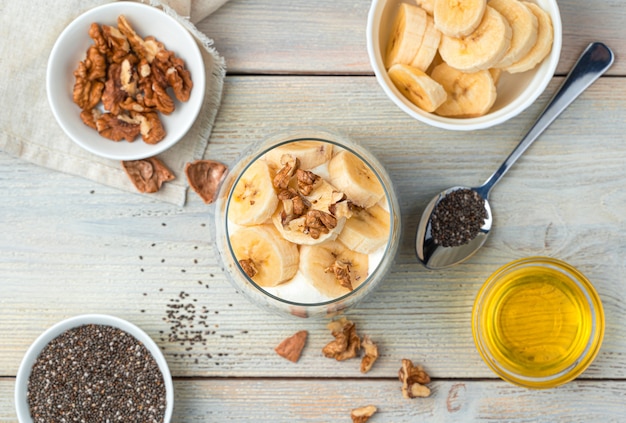 Pudim de creme de banana com sementes de chia e nozes em uma parede bege. Vista do topo.