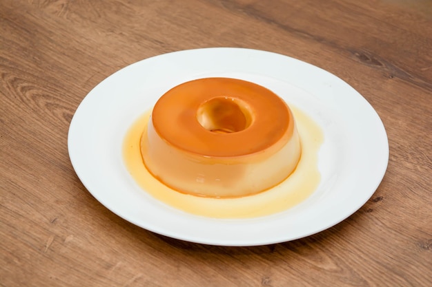 Foto pudim de leite ou pudim também conhecido como flan em uma mesa de madeira com colher metálica