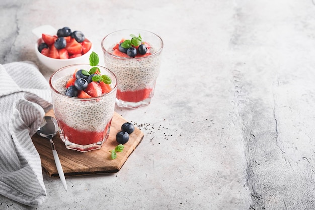 Pudim de morango Chia Café da manhã vegan saudável pudim de sementes de chia com frutas frescas e hortelã em vidro sobre fundo cinza de concreto Conceito de menu de fitness dieta alimentação saudável Foco seletivo