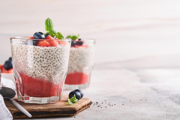 Pudim de morango Chia Café da manhã vegan saudável pudim de sementes de chia com frutas frescas e hortelã em vidro sobre fundo cinza de concreto Conceito de menu de fitness dieta alimentação saudável Foco seletivo