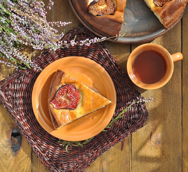 Pudim de requeijão com figos e mel no guardanapo de vime marrom e chá de ervas com heather no fundo de madeira