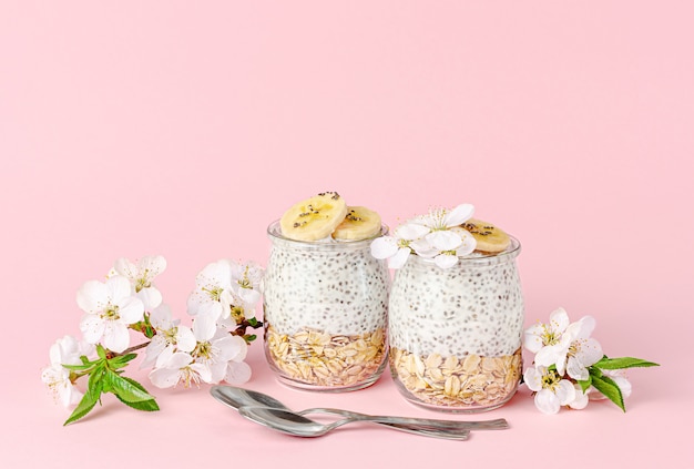 Pudim de sementes de Chia com iogurte, banana e aveia na mesa rosa pastel. Conceito de superalimento. Copie o espaço