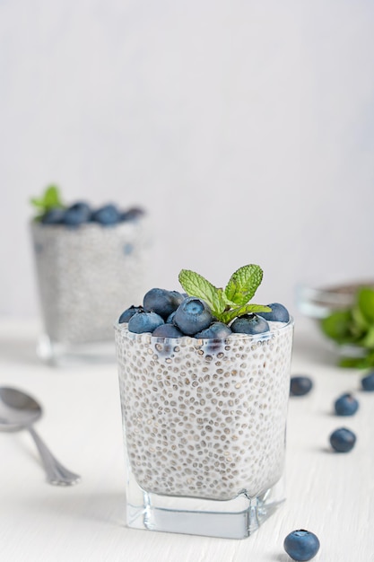 Pudim vegano de sementes de chia feito com leite vegetal decorado com frutas vermelhas e folha de hortelã servido na mesa