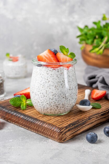 Pudín de chía con fresas frescas y arándanos encima en un frasco de vidrio.