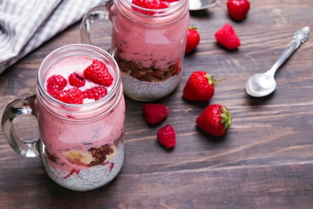 Pudín de chía con granola y fresas en un frasco de vidrio sobre la mesa de madera. Desayuno saludable.