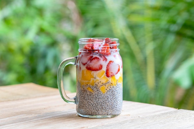 Pudín de chía con leche de almendras con fresas frescas y mango en una taza de tarro de vidrio Desayuno crudo vegano Semillas de chía y postre de frutas y bayas recién cortadas de cerca