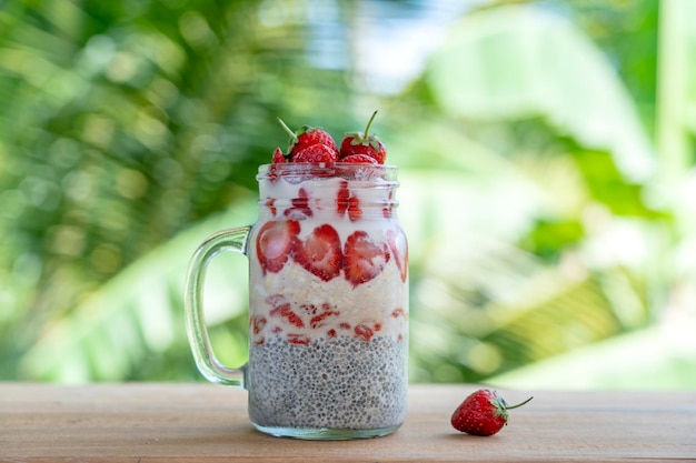 Pudín de chía con leche de almendras con fresas rojas frescas, bayas de goji y copos de avena en una taza de tarro de vidrio Desayuno crudo vegano Semillas de chía y frutas frescas cortadas y postre de bayas