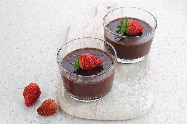 Pudín de chocolate con fresas en vidrio sobre mesa blanca Enfoque seleccionado