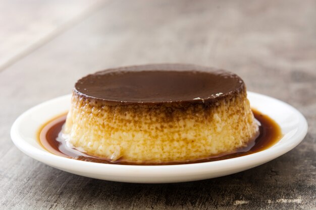 Pudin de huevo con caramelo en la mesa de madera