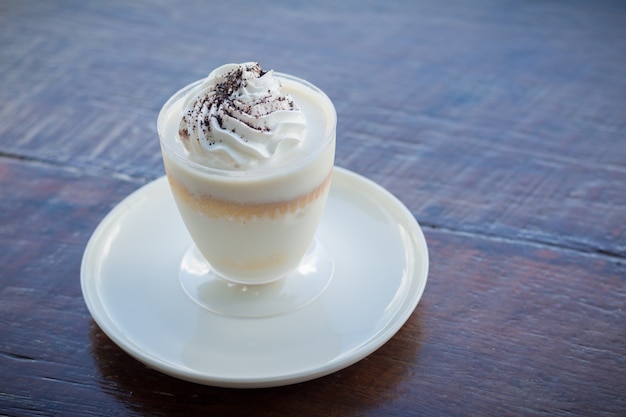 Pudín de leche delicioso con el chocolate rallado sobre la servilleta en la tabla de madera