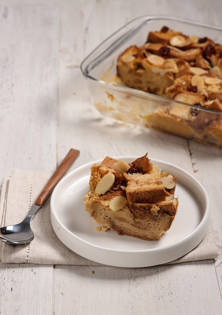 Pudín de pan o puding roti tawar cubierto con rodaja de almendra y arándano seco