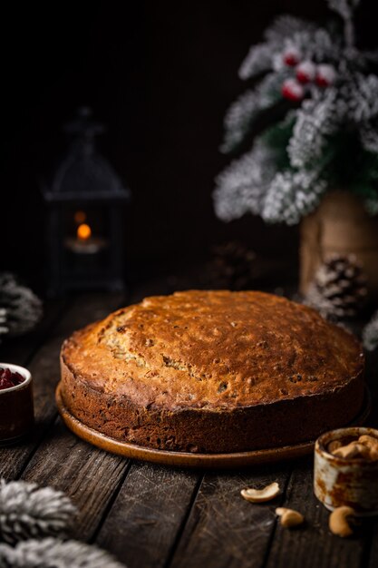 Pudín de pastel de Navidad tradicional con frutas y nueces con adornos navideños fondo oscuro