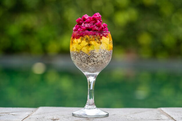 Foto pudín de semillas de chía con fruta del dragón rojo, maracuyá, mango y aguacate en un vaso para el desayuno en el fondo del agua de la piscina, de cerca. el concepto de alimentación saludable.