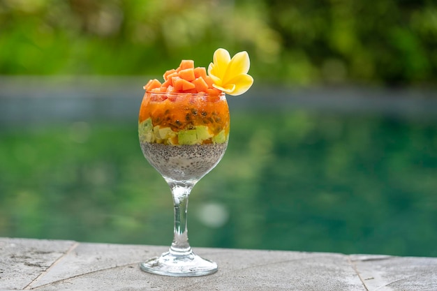 Pudín de semillas de chía con papaya, fruta de la pasión, mango y aguacate en un vaso para el desayuno en el fondo del agua de la piscina.