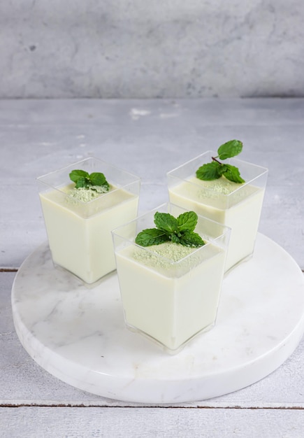 Puding matcha o té verde Pana cotta en un vaso decorado con hojas de menta