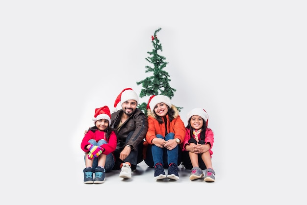 Pueblo indio celebrando la Navidad en ropa de abrigo con árbol en el fondo blanco.