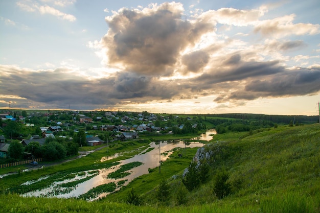 Un pueblo en la orilla del río con hierba verde brillante y un hermoso cielo