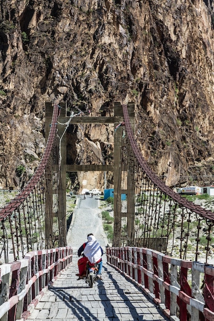 Pueblo paquistaní local en motocicletas y un puente de madera en el valle de Hunza. Pakistán