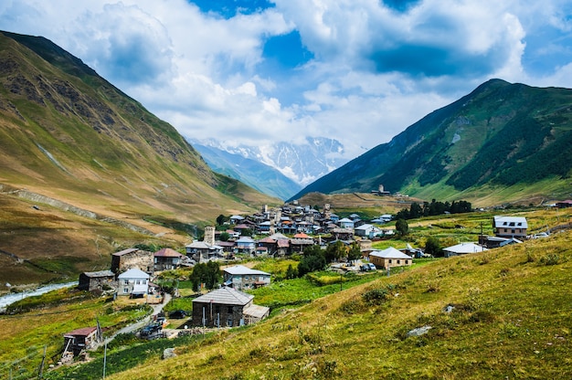 Pueblo Ushguli paisaje con enormes montañas rocosas pared Bezengi, Shkhara en el fondo en Svaneti, Georgia