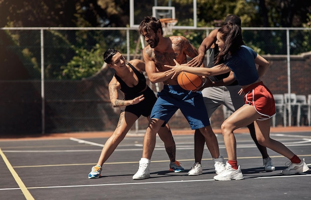 Puedes jugar baloncesto con espíritu lúdico o competitivo Foto de un grupo de jóvenes deportistas jugando baloncesto en una cancha deportiva