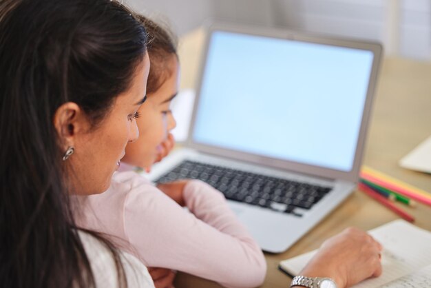 ¿Puedes leer eso por mí? Foto de una madre ayudando a su hija con su tarea en una computadora portátil.