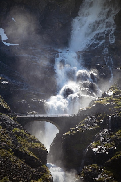 Puente de arco y cascada en la carretera Trollstigeveien - camino serpenteante en las montañas noruegas, Noruega