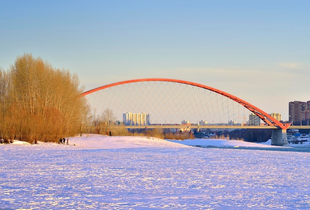 Puente de arco en el puente Bugrinsky del río Ob en la orilla nevada en la gran ciudad en primavera