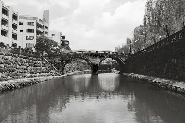 Foto puente de arco sobre el canal por el edificio contra el cielo nublado