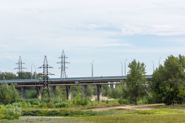 Puente de carretera que pasa por un campo con árboles y arbustos. Panorama.