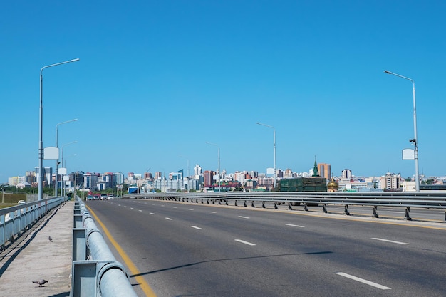 Puente de la ciudad, carretera asfaltada. Edificios modernos con carretera vacía bajo un cielo azul, Barnaul, Rusia.