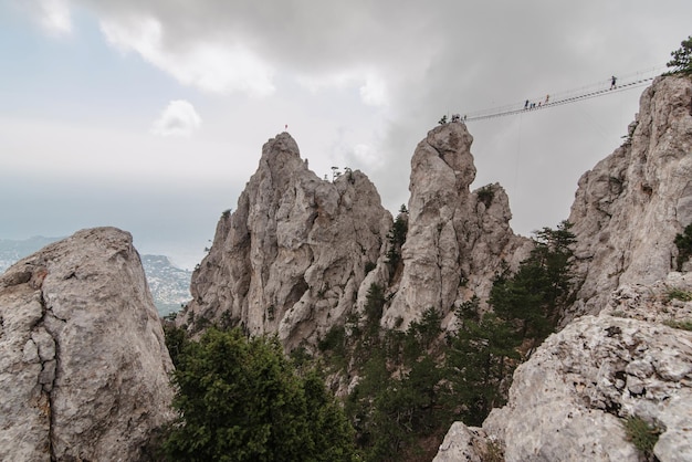 Puente colgante sobre el cañón en la cima de la montaña AiPetri en Crimea Turistas viajeros que quieren obtener adrenalina y sensaciones peligrosas