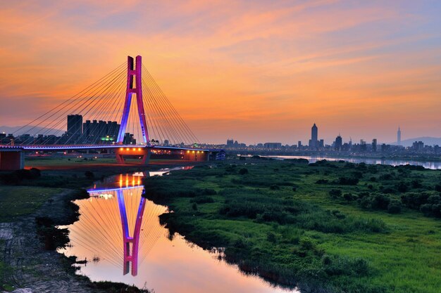 Foto puente colgante sobre el río durante la puesta del sol