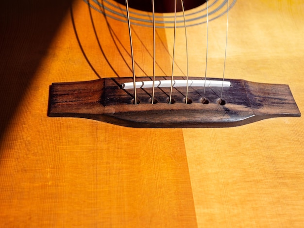 Puente de guitarra acústica con cuerdas nuevas y sin pines de puente