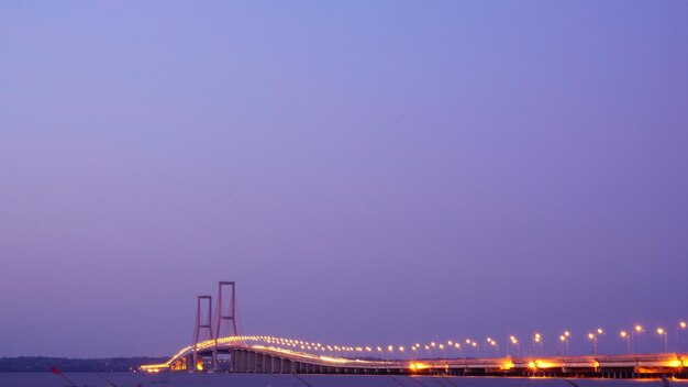 El puente se ilumina por la noche con la luna en el cielo.