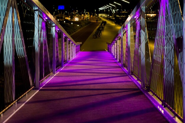 Foto puente iluminado en medio de edificios por la noche