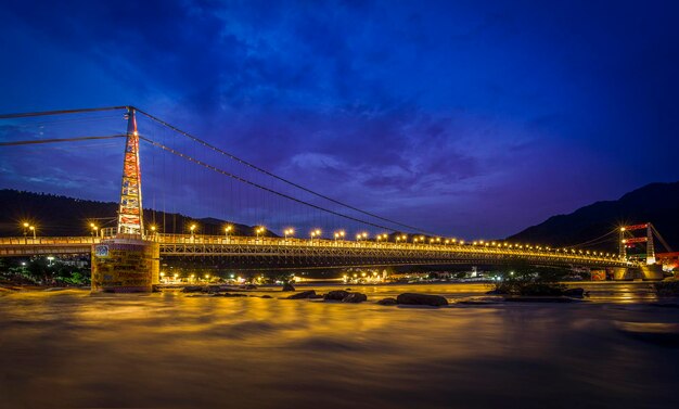 Foto puente iluminado sobre el río contra el cielo por la noche