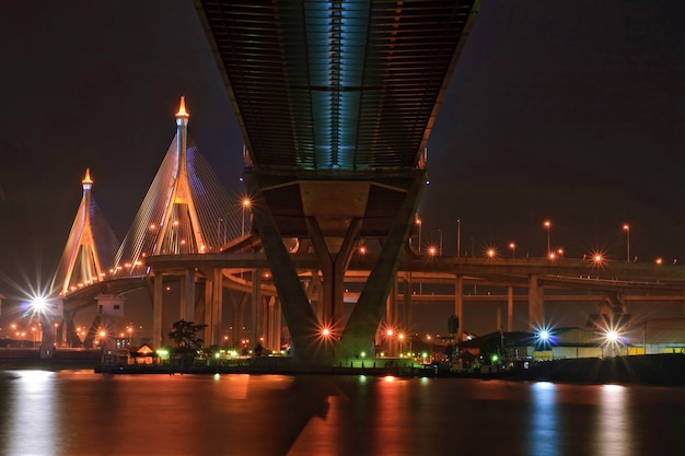 El puente industrial del anillo brilla al atardecer en Tailandia con una perspectiva central. El puente cruza el río ChaoPhraya y el puerto de Bangkok